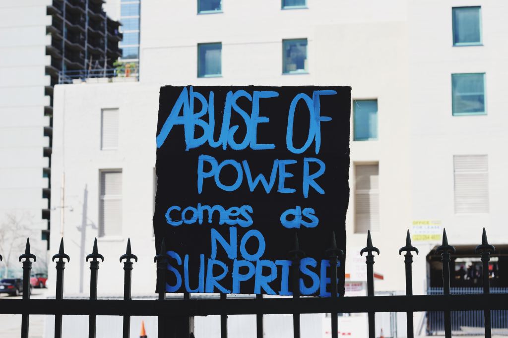 Painted sign saying "Abuse of power comes as no surprise."
