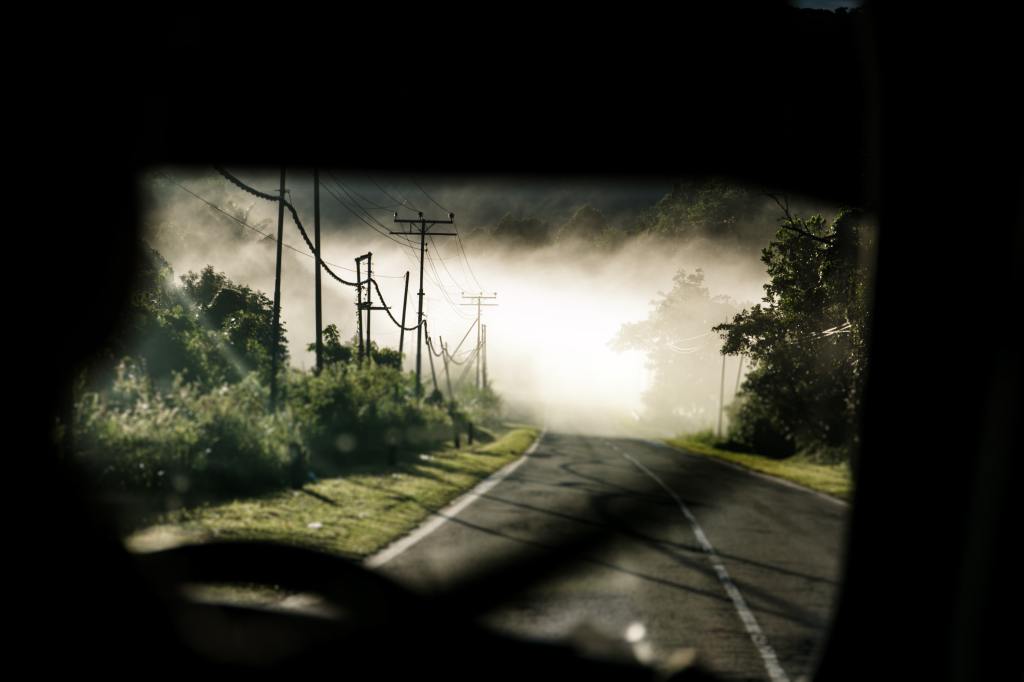 Road seen through a car's window onto a dark road.