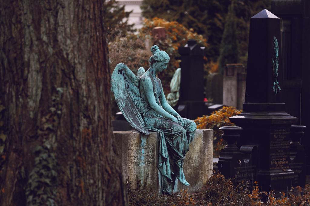 Angel statue sitting on a tomb in a German graveyard.