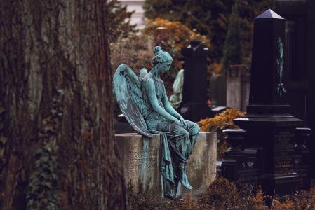 Angel statue sitting on a tomb in a German graveyard.